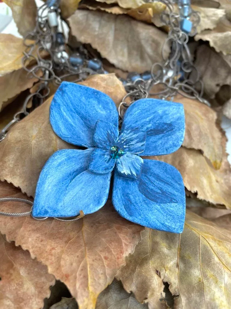 Collier multirangs de chaînes et perles, motif central : fleur d’hortensia en papier mâché teinté en bleu